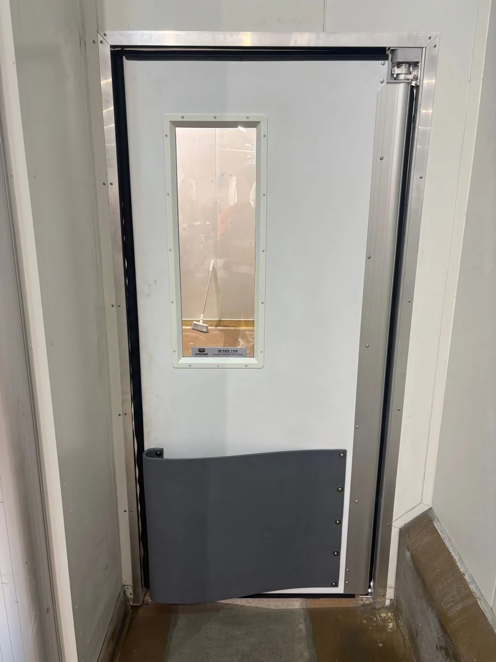 White 4500 thermal traffic swing door with a vision panel and grey buffer, installed in an aluminium frame